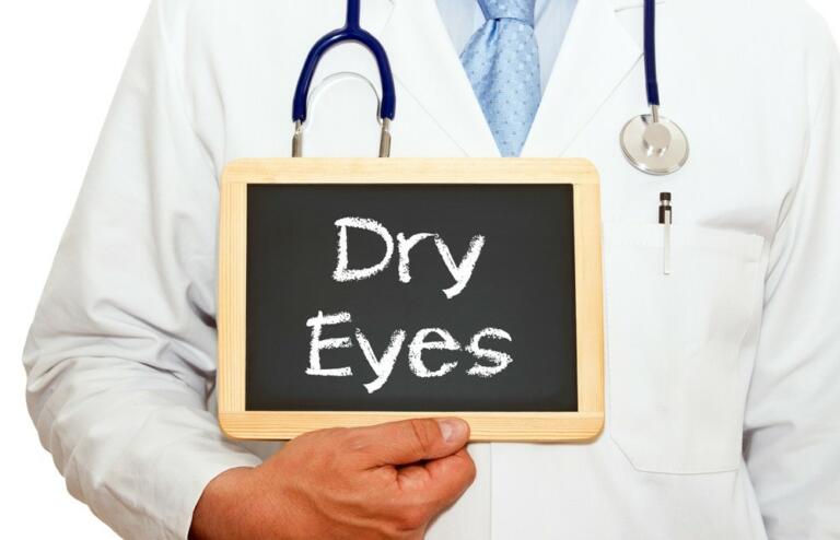 Physician holding small chalk board that reads "dry eyes".