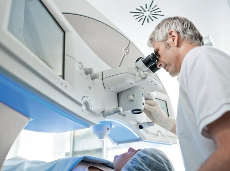 eye doctor looking into Zeiss VisuMax laser while performing SMILE eye surgery on patient