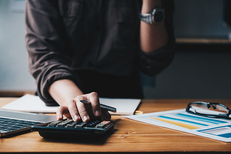 Business woman entrepreneur using a calculator with a pen in her