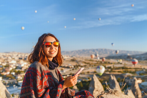 Tourist woman with her phone and hot air balloons in the background