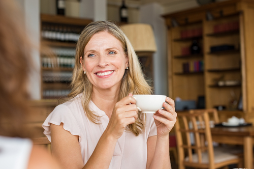 Mature woman holding coffee cup and talking with friend