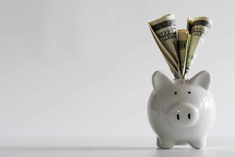 America dollars banknotes money into piggy bank on white background.