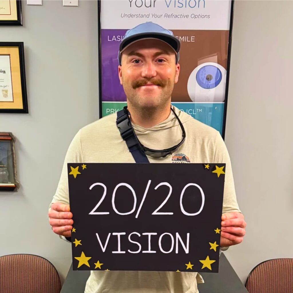 Happy post-op PRK (photorefractive keratotomy) patient at LaserVue Eye Center smiles for the camera while holding a sign that reads "20/20 Vision"