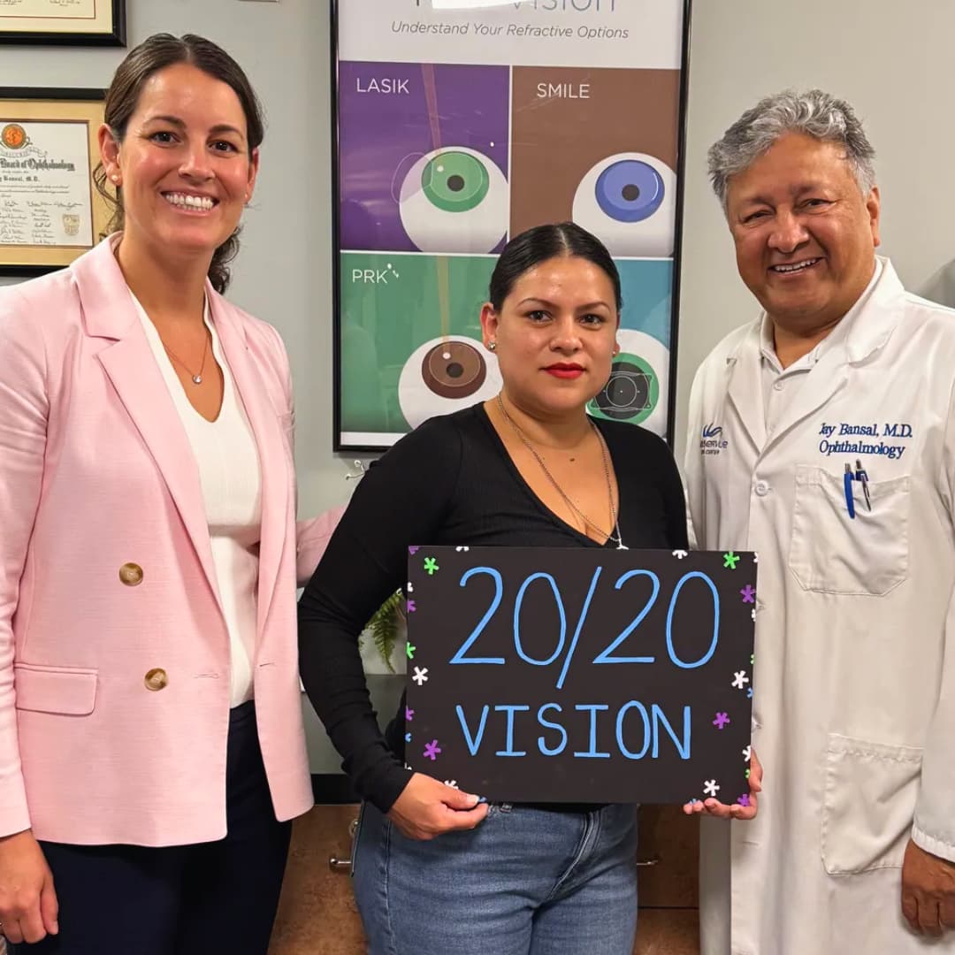 Celia C LASIK 20/20 vision patient standing with Dr. Jay Bansal and Dr. Francesca Sefton, holding a sign that reads "20 20 vision"