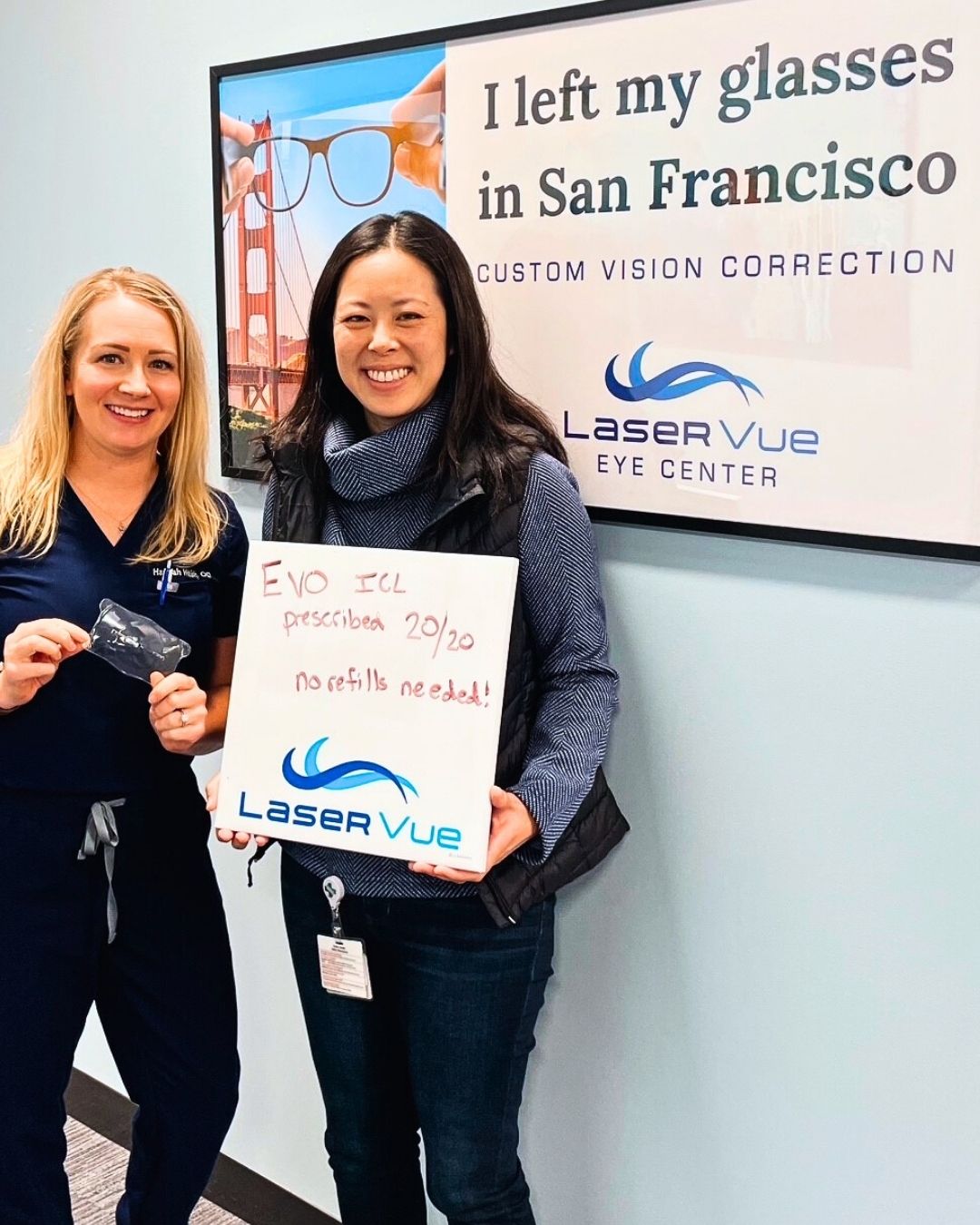 Dr. Nicole Luu, PharmD, BCPS, stands with Dr. Hannah Walsh, optometrist at LaserVue Eye Center. Dr. Luu is holding a whiteboard that reads "Prescribed EVO ICL, 20/20, no refills needed! LaserVue." Dr. Luu and Dr. Walsh are standing in front of a poster that reads "I left my glasses in San Francisco. Custom Vision Correction. LaserVue Eye Center."