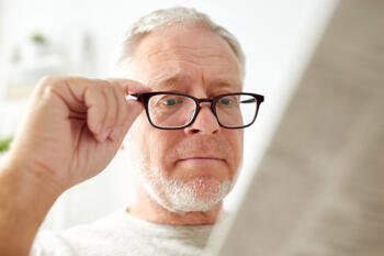 middle aged man using glasses to read newspaper