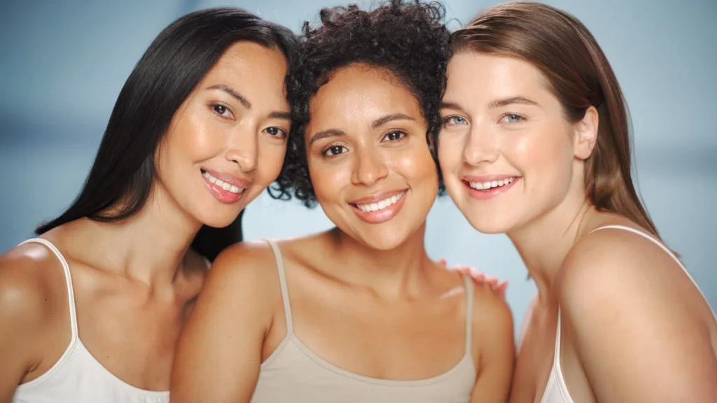 Three women with clear skin smiling together