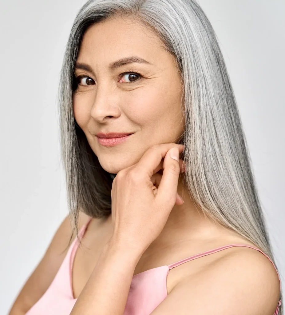 Woman with silver hair touching her cheek
