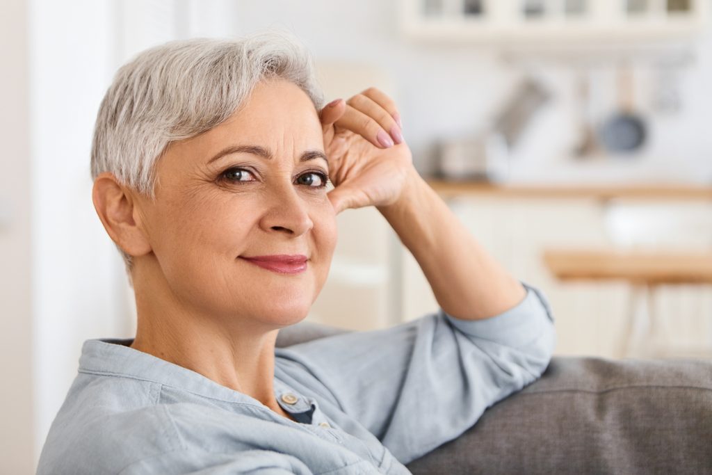 Relaxed older woman smiling with her hand on her cheek