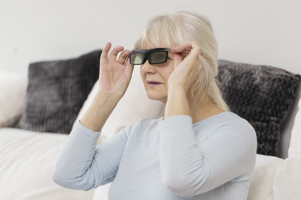 Older woman trying on dark glasses at home