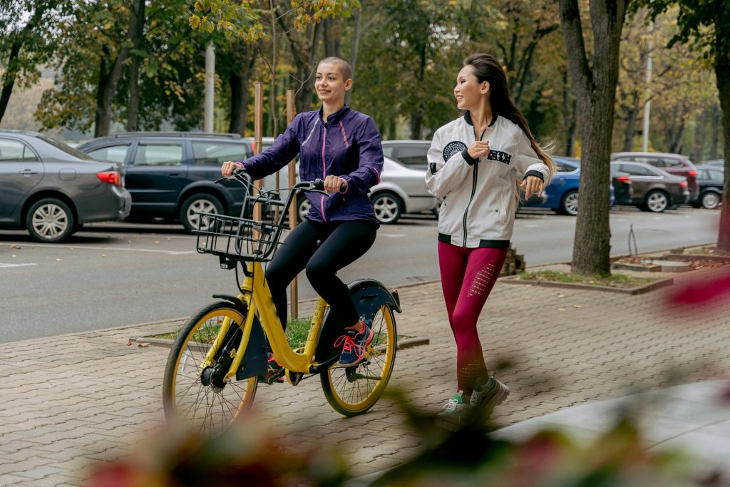 Two women walking with a bicycle outdoors