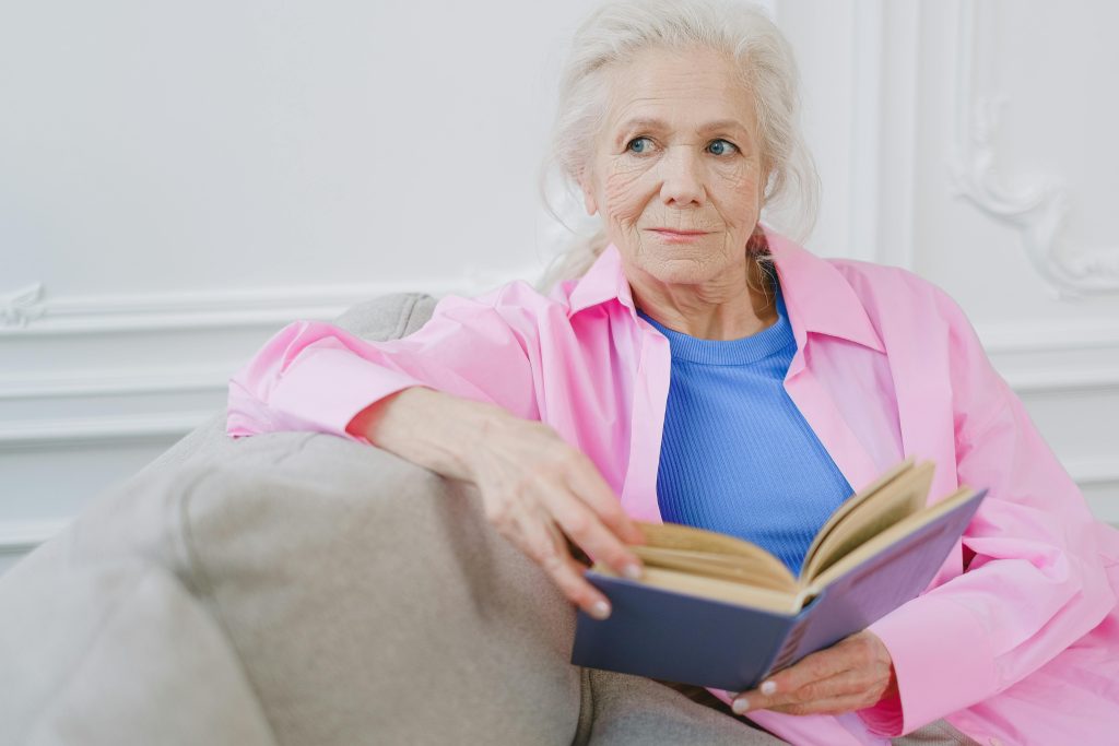 Older woman reading a book on a couch