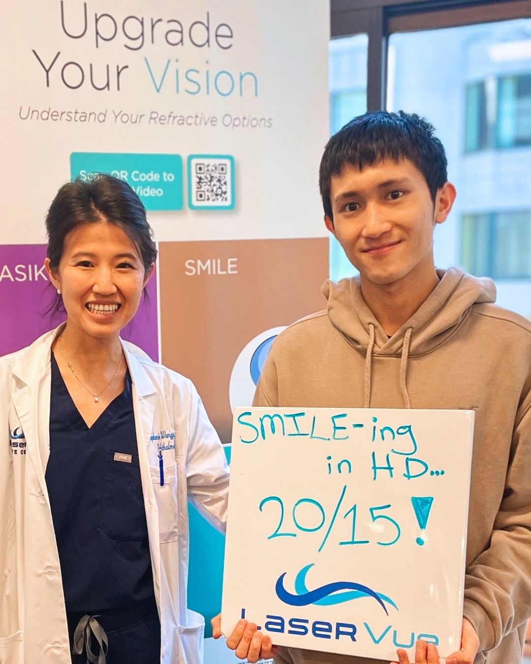LaserVue SMILE patient holding a 20/15 vision sign with a team member
