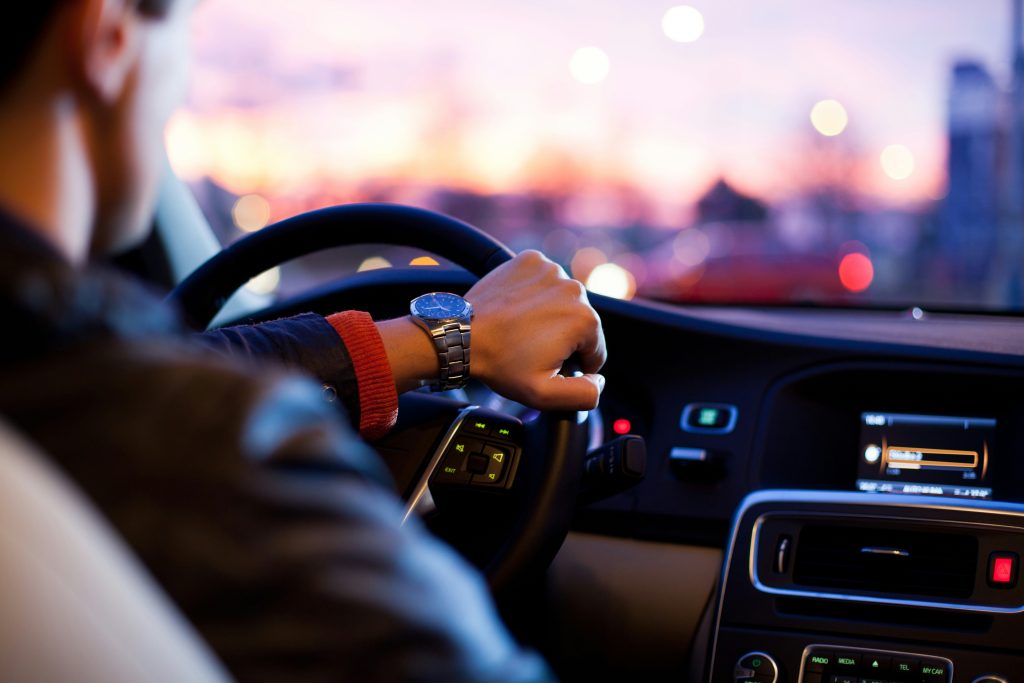 Driver's hands on a steering wheel at night with blurred city lights