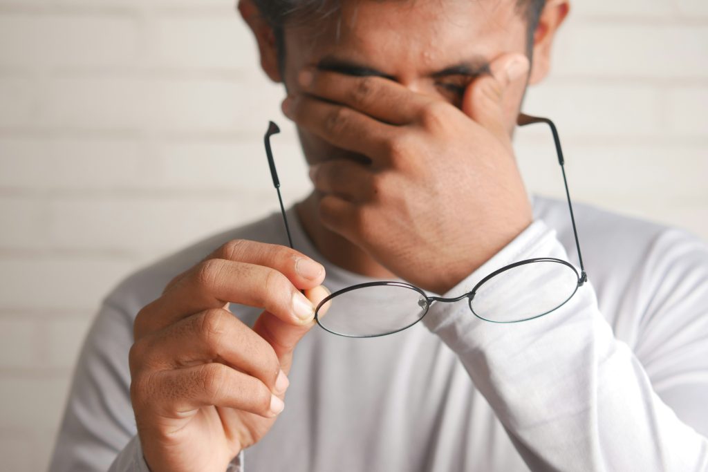 Man taking off his glasses to rub his tired eyes