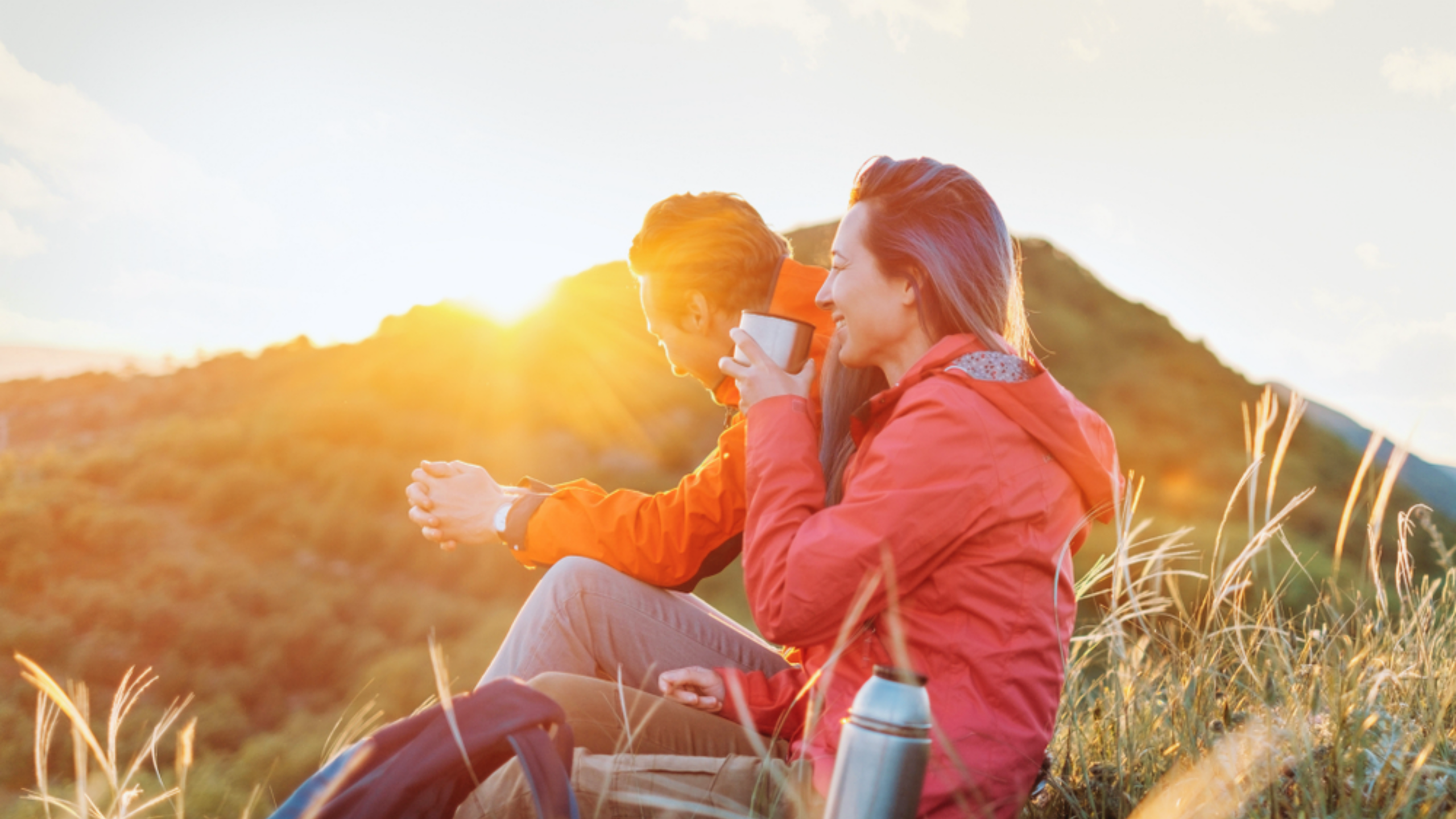 Couple sitting and having breakfast on top of a sunny hill in the morning