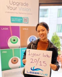 A PRK post-op patient at LaserVue Eye Center, Alice W, stands in front of a poster that reads "Upgrade Your Vision. Understand your refractive options. LASIK. SMILE. PRK. EVO ICL." She is holding a white board that reads "1 year later 20/15. LaserVue."