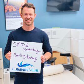 SMILE patient at LaserVue Eye Center holds a sign that reads "SMILE yesterday... Smiling today! LaserVue"