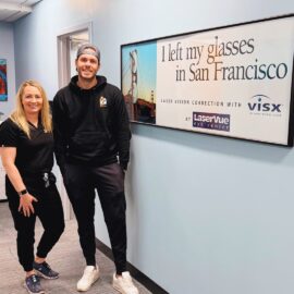 Happy LASIK patient stands with Dr. Hannah Walsh next to a sign that reads "I left my glasses in San Francisco. Laser Vision Correction with LaserVue Eye Center"
